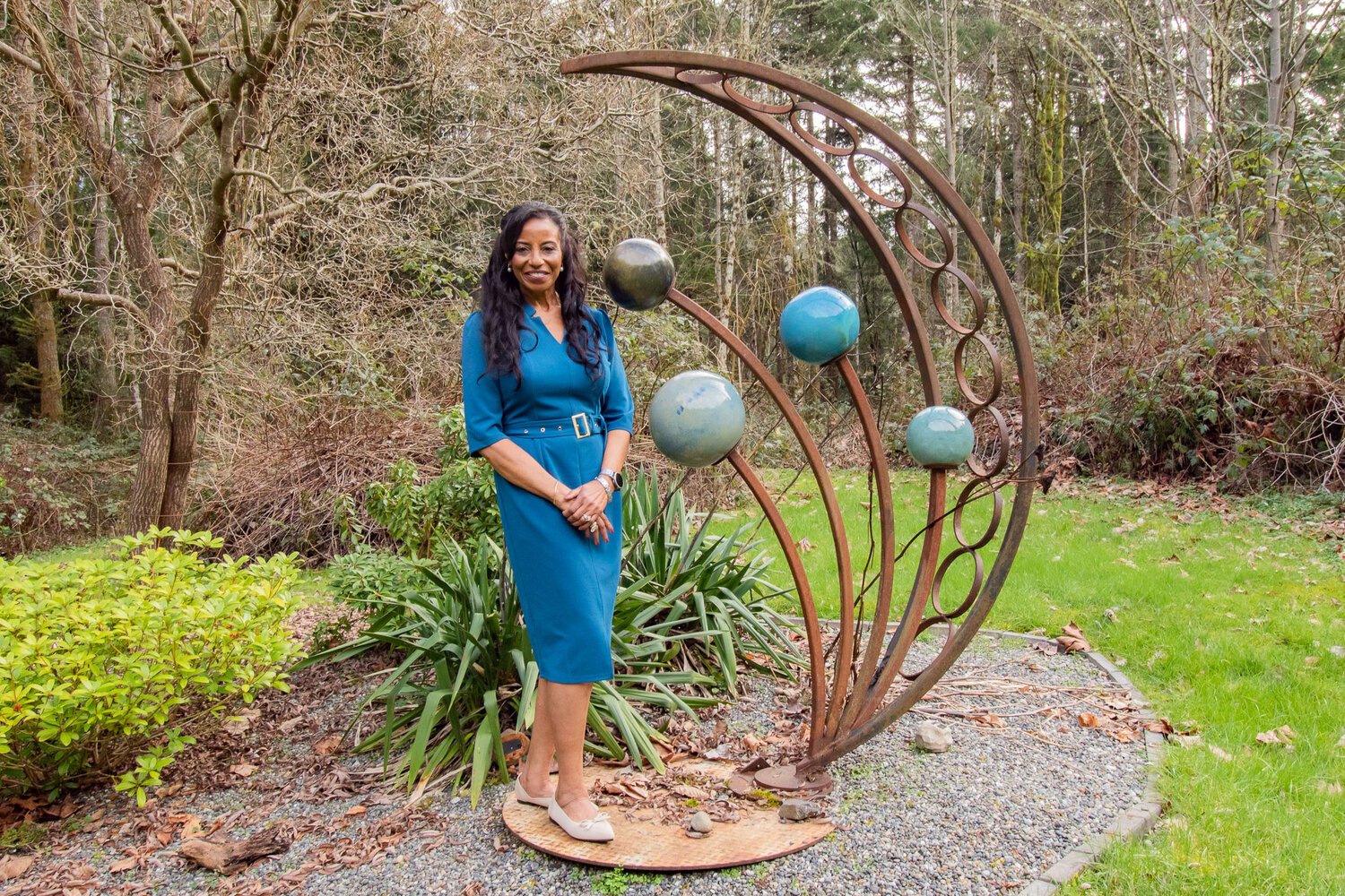 Miss Lewis County 1976 Josseline Mangin stands next to a metal and glass crescent on Feb. 27, at her Puget Sound home in Poulsbo.